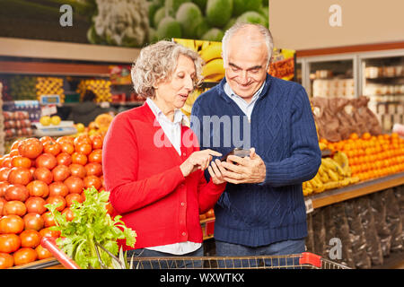 Paar Senioren als Verbraucher nutzt Smartphone App für den Preisvergleich Stockfoto