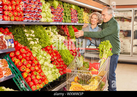 Senior Paar mit Warenkorb zusammen beim Kaufen Gemüse im Supermarkt Stockfoto