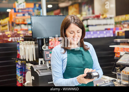 Lächelnde Frau als Kassierer mit einem Barcode Scanner an der Supermarkt Kasse Stockfoto