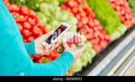 Kunde nutzt Barcode Scanner App im Supermarkt beim Einkaufen Erdbeeren Stockfoto