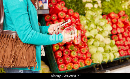 Frau nutzt Barcode Scanner App im Smartphone beim Einkauf für Erdbeeren im Supermarkt Stockfoto