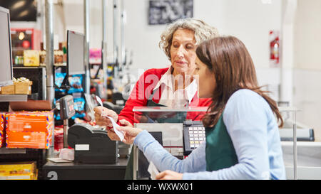 Kunde und Kasse gemeinsam prüfen eine Quittung im Supermarkt Stockfoto