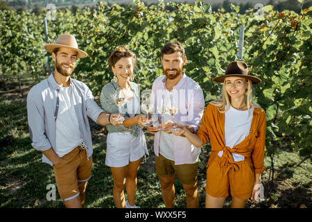 Portrait einer jungen stilvoll Freunde stehend mit Weingläsern, heraus zusammen hängen auf dem Weinberg an einem sonnigen Sommermorgen Stockfoto