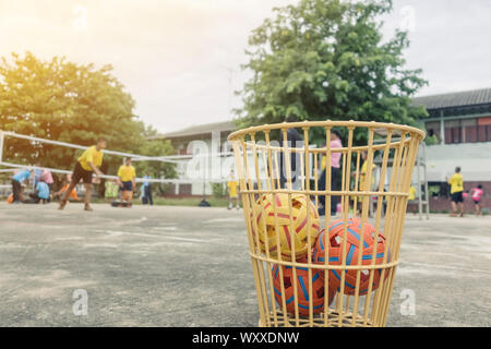 Die takraws im Kunststoff Warenkorb auf dem Zementboden neben dem Feld ist für Schüler verwendet, die in der Physischen Ausbildung Stunden zu üben. Stockfoto