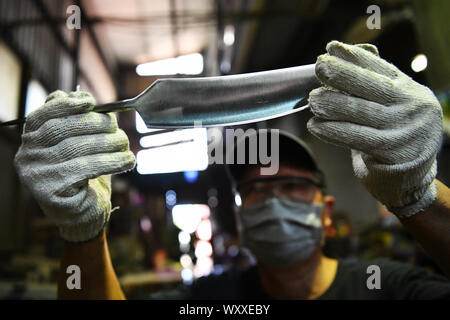 Kinmen, China. 18 Sep, 2019. Ein Handwerker blickt auf eine fast fertige Kinmen stahl Messer auf einem Workshop im Südosten Chinas Kinmen auf Sept. 18, 2019. Der Stahl Messer mit Rohstoffen von weggeworfenen Schalen geschmiedet ist eine berühmte Produkt der Kinmen. Credit: Chen Bin/Xinhua/Alamy leben Nachrichten Stockfoto