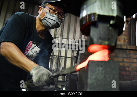 Kinmen, China. 18 Sep, 2019. Ein Handwerker schmieden Kinmen stahl Messer auf einem Workshop im Südosten Chinas Kinmen auf Sept. 18, 2019. Der Stahl Messer mit Rohstoffen von weggeworfenen Schalen geschmiedet ist eine berühmte Produkt der Kinmen. Credit: Chen Bin/Xinhua/Alamy leben Nachrichten Stockfoto