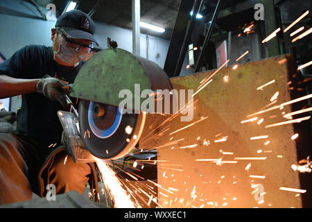 Kinmen, China. 18 Sep, 2019. Ein Handwerker poliert Kinmen stahl Messer auf einem Workshop im Südosten Chinas Kinmen auf Sept. 18, 2019. Der Stahl Messer mit Rohstoffen von weggeworfenen Schalen geschmiedet ist eine berühmte Produkt der Kinmen. Credit: Chen Bin/Xinhua/Alamy leben Nachrichten Stockfoto