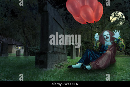 Scary Clown mit Luftballons in der Hand auf einem Friedhof Stockfoto