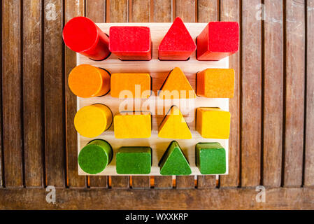 Satz von Bausteinen aus Holz von Sequenzen von geometrischen Formen mit Naturfarben bemalt, von oben gesehen, die motorische Entwicklung der Kinder zu helfen. Stockfoto