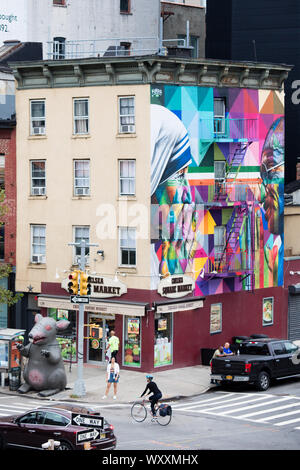 Straße Ecke Szene mit Radfahrer, Ampeln, Wandgemälde und Chelsea Square Markt Store an der West 18. Straße und Zehnten Avenue in New York City, USA Stockfoto