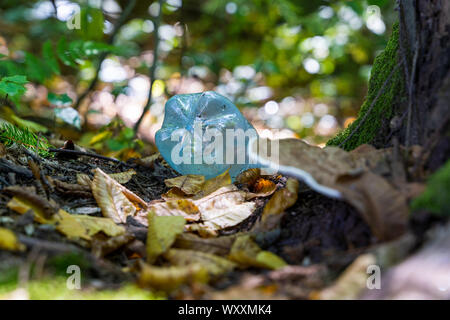 Eine blaue Leere Wasserflasche weggeworfen. Solche Abfälle aus Kunststoff ist ein allgemeines Problem in einem städtischen Gebiet, sondern auch in Wäldern regelmäßig gefunden, das ist eine im Stockfoto