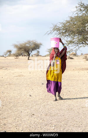 Arusha, Tansania, 7. September 2019: Massai-frau mit einem Wassereimer auf dem Kopf Stockfoto