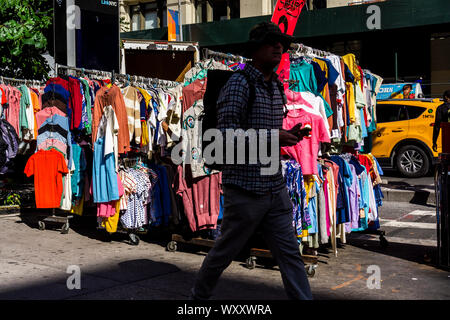 Menschen gehen vorbei an einem Straßenhändler verkaufen chinesische und andere asiatische Bekleidung am Freitag hergestellt, 13. September 2019. (© Richard B. Levine) Stockfoto