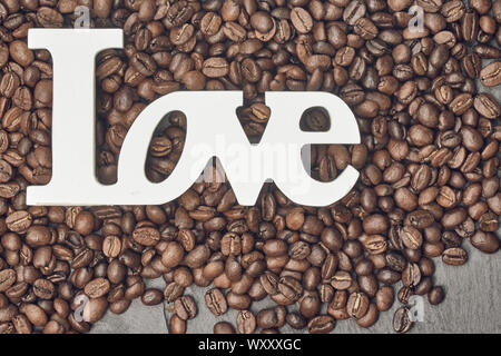 Kaffeebohnen und einem weißen Liebe zeichen Draufsicht auf schiefer Hintergrund Stockfoto