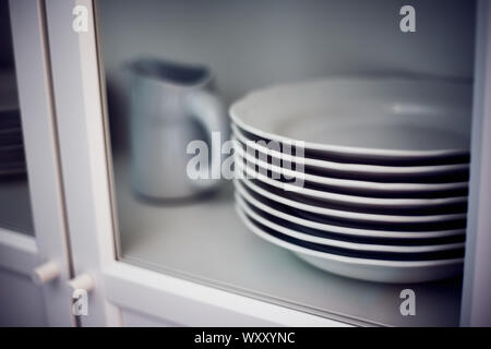 Nahaufnahme einer vintage Anrichte mit Steingut Teller und Kanne in die Fenster, Geschirr Stockfoto