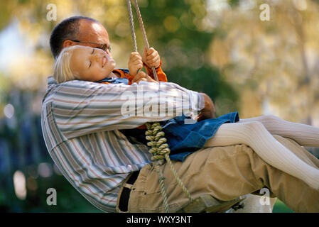 Mädchen genießt Schwingen auf Baum Schwingen mit ihrem Vater. Stockfoto