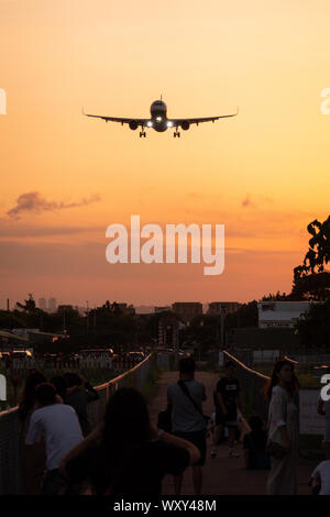 Zuschauer verfolgen und Fotos von "Flugzeug Alley", als ein Airbus A321 sein, Taipei Songshan Airport macht in der Dämmerung Stockfoto