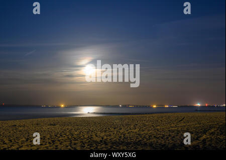 Mondaufgang am Meer von Usedom, Deutschland. Im Dunst am Horizont sehen die Lichter an der polnischen Küste. Stockfoto