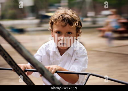 Ein kleiner Junge hat Angst, er hält den Stab von Merry-go-round. Stockfoto