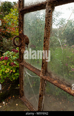 Alten rostigen Fenster mit gerissenen Scheiben auf einen Garten Stockfoto