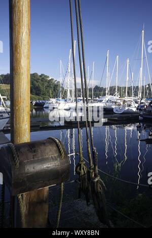 Yachten vor Anker auf eine Marina mit blauem Himmel und Reflexionen der Mast und Rigg auf dem Wasser Stockfoto