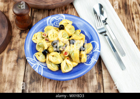 Tortellini mit Oliven auf hölzernen Tisch Stockfoto