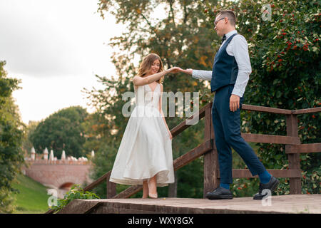 Hochzeit paar auf Treppen im Park. Bräutigam im blauen Anzug Hand, die schöne Braut im weißen Kleid. Sehr schöne Hochzeit von erstaunlichen Paar. Gehen zu Stockfoto