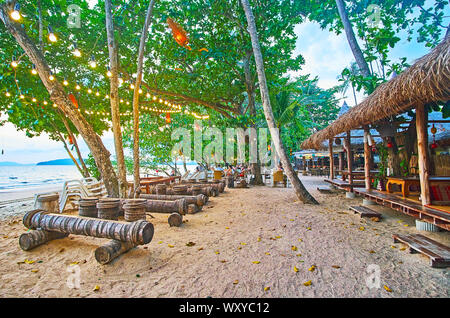 AO NANG, THAILAND - 25 April 2019: Die üppige tropische Vegetation versteckt den Holzhütten des Strandcafés und Bars mit Terrassen und gemütliche open air Lounge zo Stockfoto