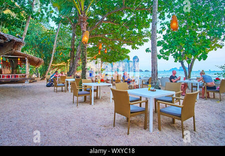 AO NANG, Thailand - 25 april, 2019: Das Abendessen im Restaurant an der Küste, im Schatten der Bäume versteckt und mit Blick auf die Tonsai Bay und Ao Nang Tower Stockfoto