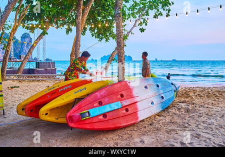 AO NANG, THAILAND - 25 April 2019: Die bunten Boote zum Mieten am Strand, neben der Lounge Cafes und Bars, am 25. April in Ao Nang Stockfoto