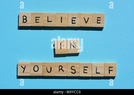 Glauben Sie an sich selbst, motivierende Angebot in Holz- Alphabet Buchstaben auf einem blauen Hintergrund Stockfoto