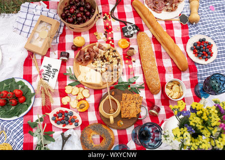Stilvolles Picknick auf der grünen Wiese. Frische Croissants und eine Teekanne mit Tee auf eine Bettdecke in der Nähe eines Wicker weibliche Hut. Instagram Inhalt. Stockfoto
