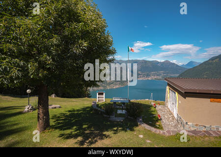 Blick auf den Luganersee, den Berg Pizzoni und die italienische Flagge von Cappelletta di Ramponio-Verna in der Region Como, Norditalien Stockfoto