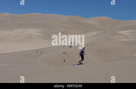 Wanderer und Sand sledders den Dünen am Great Sand Dunes National Park Klettern im Sommer in Colorado. Stockfoto