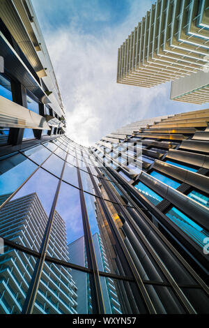 Hohe Wolkenkratzer in der Innenstadt mit schönen Reflexion auf glänzenden Fenstern. Modernes hohes Gebäude auf und blauer Himmel. Architektonisches detail. Stockfoto
