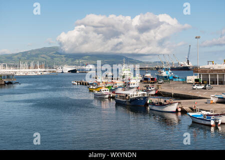 Boote im Hafen von Ponta Delgada auf der Insel São Miguel mit einer großen Wolke über vulkanischen Hügel der Insel sitzen auf einem hellen Tag. Stockfoto