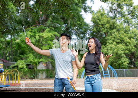 Junge asiatische Paar im Park spielen mit Blasen Stockfoto