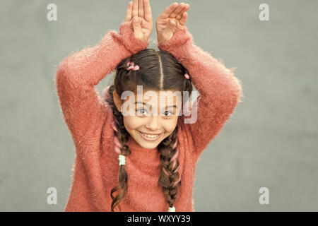 Cute Bunny. Frohe Ostern. Urlaub Bunny Girl posiert wie Kaninchen grauen Hintergrund. Kind lächelnd spielen Bunny Rolle. Verspieltes Baby feiern Ostern. Frühlingsferien. Talent und Handeln. Glückliche Kindheit. Stockfoto