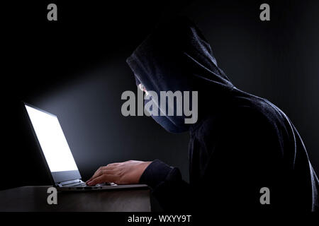 Cyberkriminalität, Hacking und Kriminalität. Hacker mit Laptop. mit Freistellungspfaden. Stockfoto