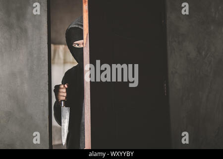 Der Dieb hält ein Messer die Haustür für Raub zu öffnen. Stockfoto