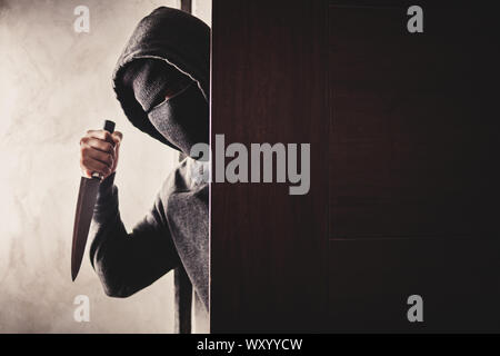 Der Dieb hält ein Messer die Haustür für Raub zu öffnen. Stockfoto