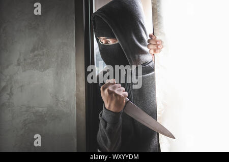 Der Dieb hält ein Messer die Haustür für Raub zu öffnen. Stockfoto