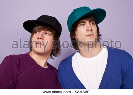 Zwei Jungs im Teenageralter tragen Basecaps wegsehen, Studioaufnahme Stockfoto