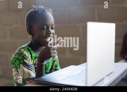 Adorable niña africana sorprendido mirando la tecnología informática portátil