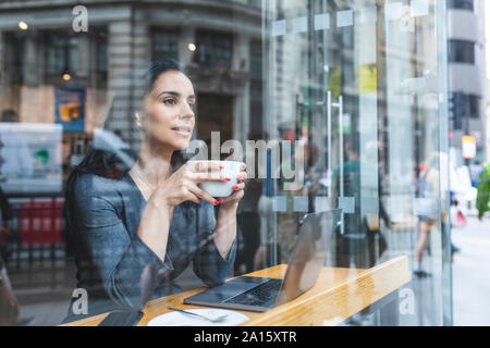 Mujer de negocios tomando un café y mirar por la ventana