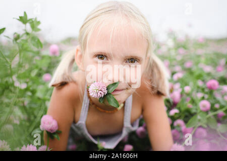Retrato de niña sonriente con flor de trébol en su boca