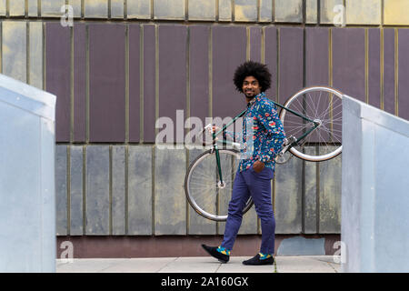 Hombre elegante llevar la bicicleta en la ciudad