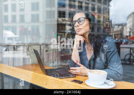 Mujer de negocios tener un descanso en una cafetería y trabajando con un portátil
