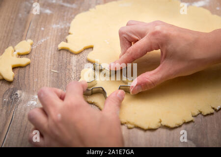 Mujer con una cookie cutter y en forma de estrella de masa fresca cruda, mesa de madera Foto de stock