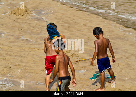 Unknown niños jugando con la arena y el agua por el río Belaga en Sarawak, Malasia Foto de stock